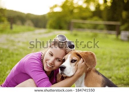 Happy young woman with her beagle dog in the green park