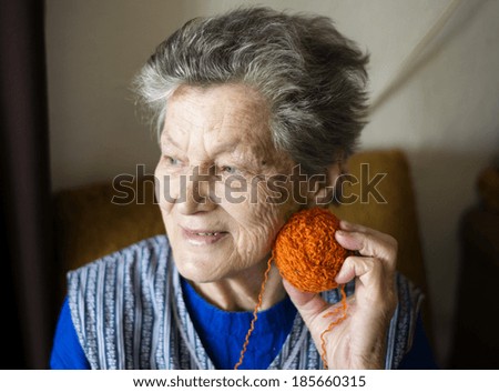 Portrait of senior woman sitting in armchair and knitting at home
