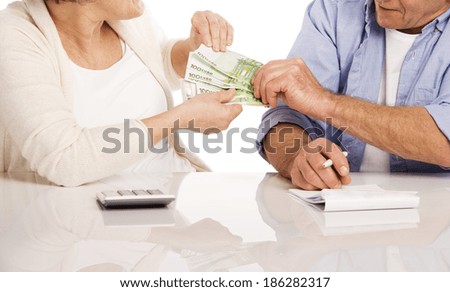Senior couple counting money at the table, isolated on white background