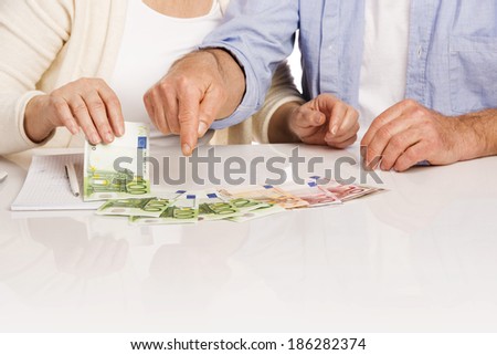 Senior couple counting money at the table, isolated on white background