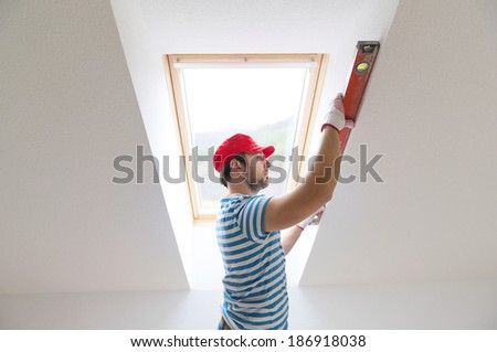 Young man measuring the wall of new home with level