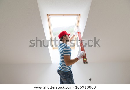Young man measuring the wall of new home with level