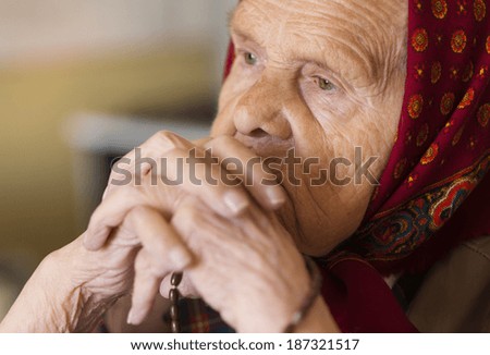 Detail of very old woman in head scarf praying
