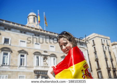 Happy woman tourist is walking in the city street of Barcelon with spanish flag.