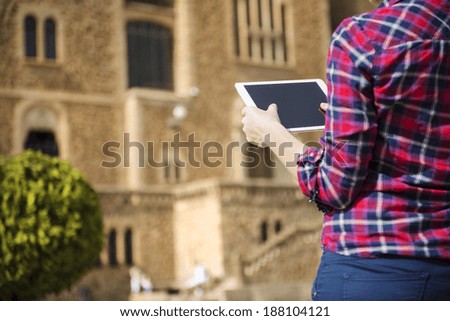 Pretty young female tourist using electronic tablet in front of the church in Barcelona, Spain.
