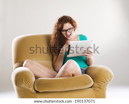 Beautiful girl with digital tablet sitting on armchair, isolated on white background