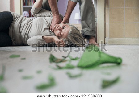 Woman victim of domestic violence and abuse. Mature woman scared of a man with broken bottle
