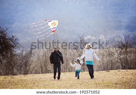 Happy pregnant family having fun with kite in autumn nature