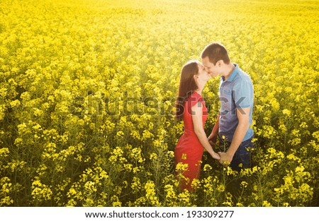 Happy young couple in love kissing in yellow colza field