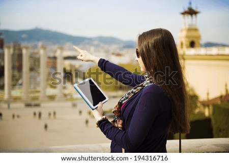 Pretty young female tourist using digital tablet and enjoying the view in Barcelona, Spain.