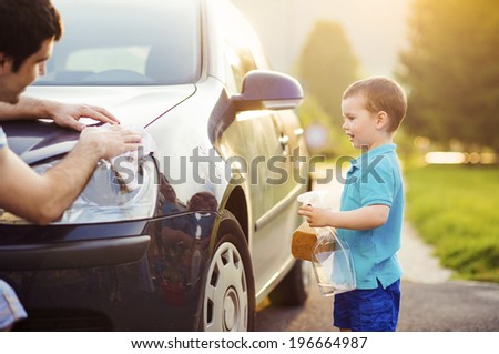 Young father with his little son washing car