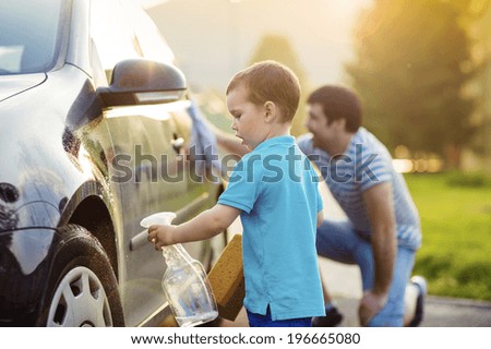 Young father with his little son washing car