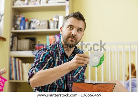 Man holding damaged CD sitting on florr in bedroom
