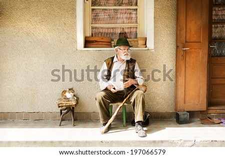 Old man reading the newspaper in front of his house