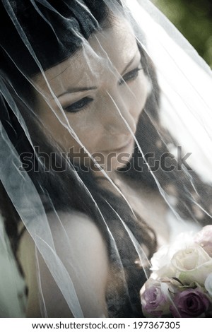 Portrait of beautiful brunette bride with veil and bouquet