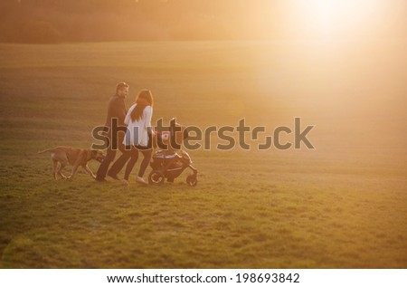 Happy and young family with pram and dog during the walk in nature