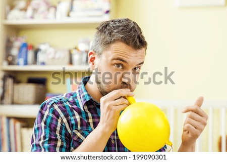happy father is blowing yellow balloon at home