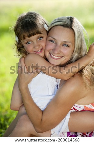 Mother and little daughter hugging together in summer garden.