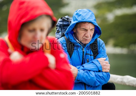 Senior tourist couple hiking at the beautiful mountains in cold weather