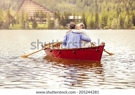 Senior couple paddling on boat with mountains in background
