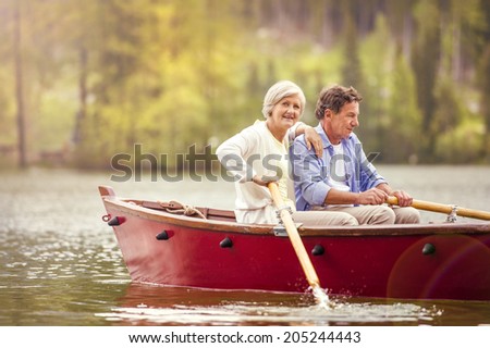 Senior couple paddling on boat with mountains in background