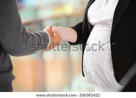 Unrecognizable businessman and businesswomen having a meeting in shopping mall. Woman is pregnant.