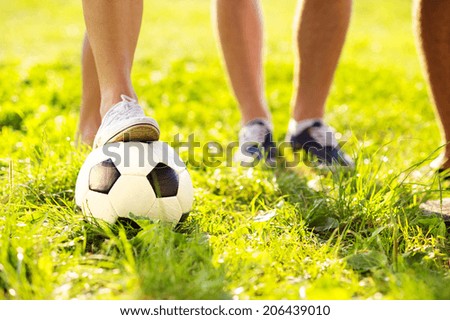 close up of feet and football ball on green grass lawn