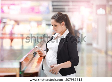 Busy pregnant woman talking on the phone in shopping mall