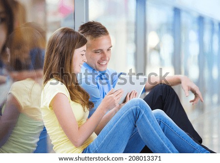 Smiling couple having fun with digital tablet in shopping mall