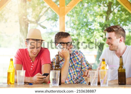 Three happy friends drinking and having fun in pub garden