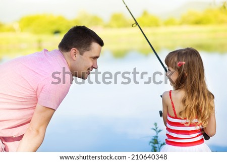 Happy young father fishing on the lake with his little daughter