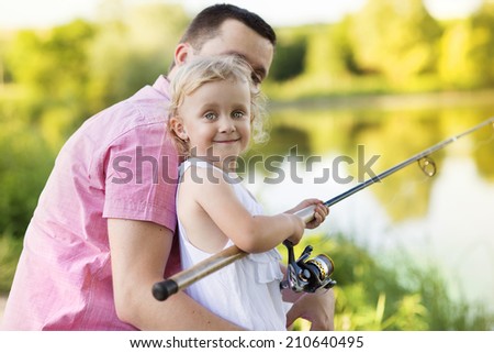 Happy young father fishing on the lake with his little daughter