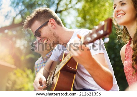 Group of happy friends with guitar having fun outdoor