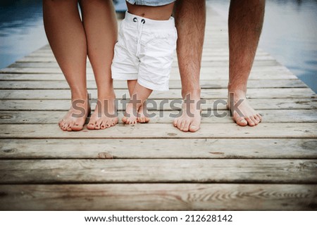 Closeup of feet of family with little baby boy walking on pier