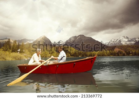 Senior couple paddling on boat on mountain tarn