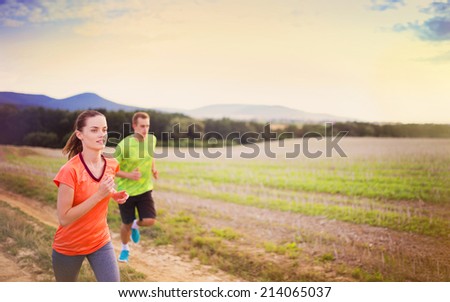 Cross-country trail running people at sunset. Runner couple exercising outside as part of healthy lifestyle.