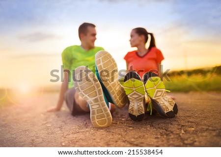 Cross-country trail running couple stretching and exercising at sunset