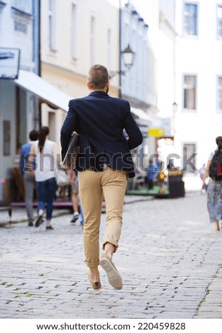 Handsome modern hipster businessman with briefcase hurrying to work