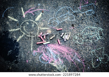 Child's drawing of sun and colorful chalks on a street
