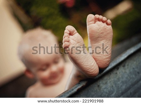 Cute funny little boy bathing in galvanized tub outdoor in green garden, close up of feet