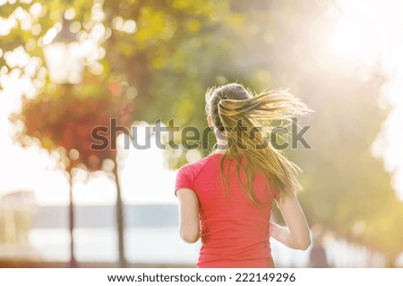Young female runner is jogging in the city on a quay. Sport lifestyle.