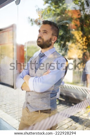 Handsome hipster modern man waiting for bus on bus stop