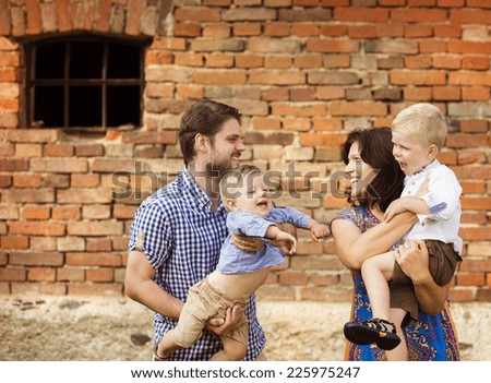 Happy young family have fun together in nature by the old brick house