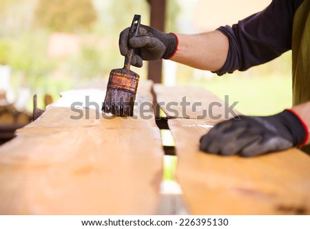 Varnishing of pine wooden planks, workers hand and paintbrush