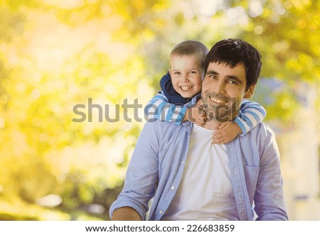 Father and son spending time together in sunny nature, son is hugging father