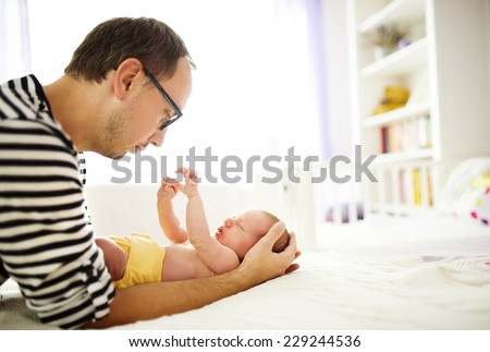 Happy young father enjoying special moments with his newborn baby daughter at home