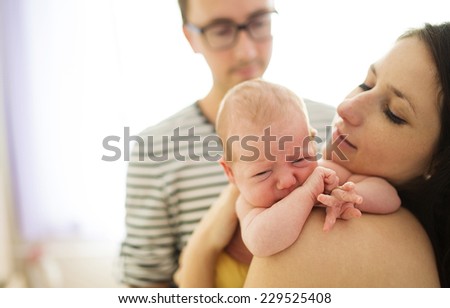 Happy young parents with their crying newborn baby girl at home