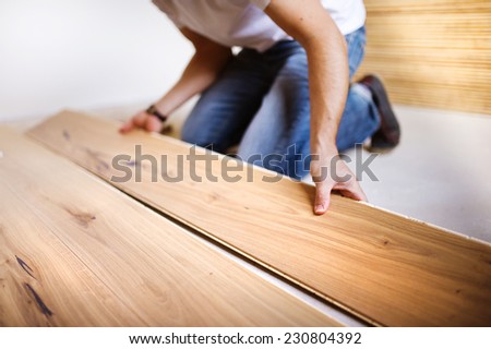 Unrecognizable handyman installing wooden floor in new house