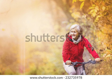 Active senior woman ridding bike in autumn nature.