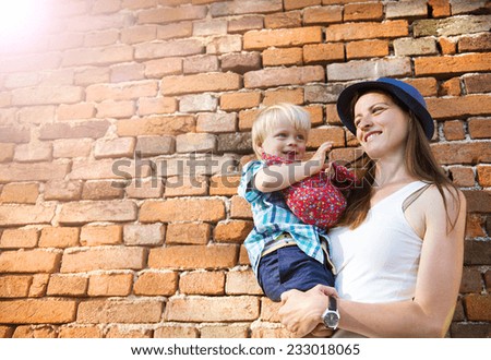Mother and son hugging by the brick wall in countryside.